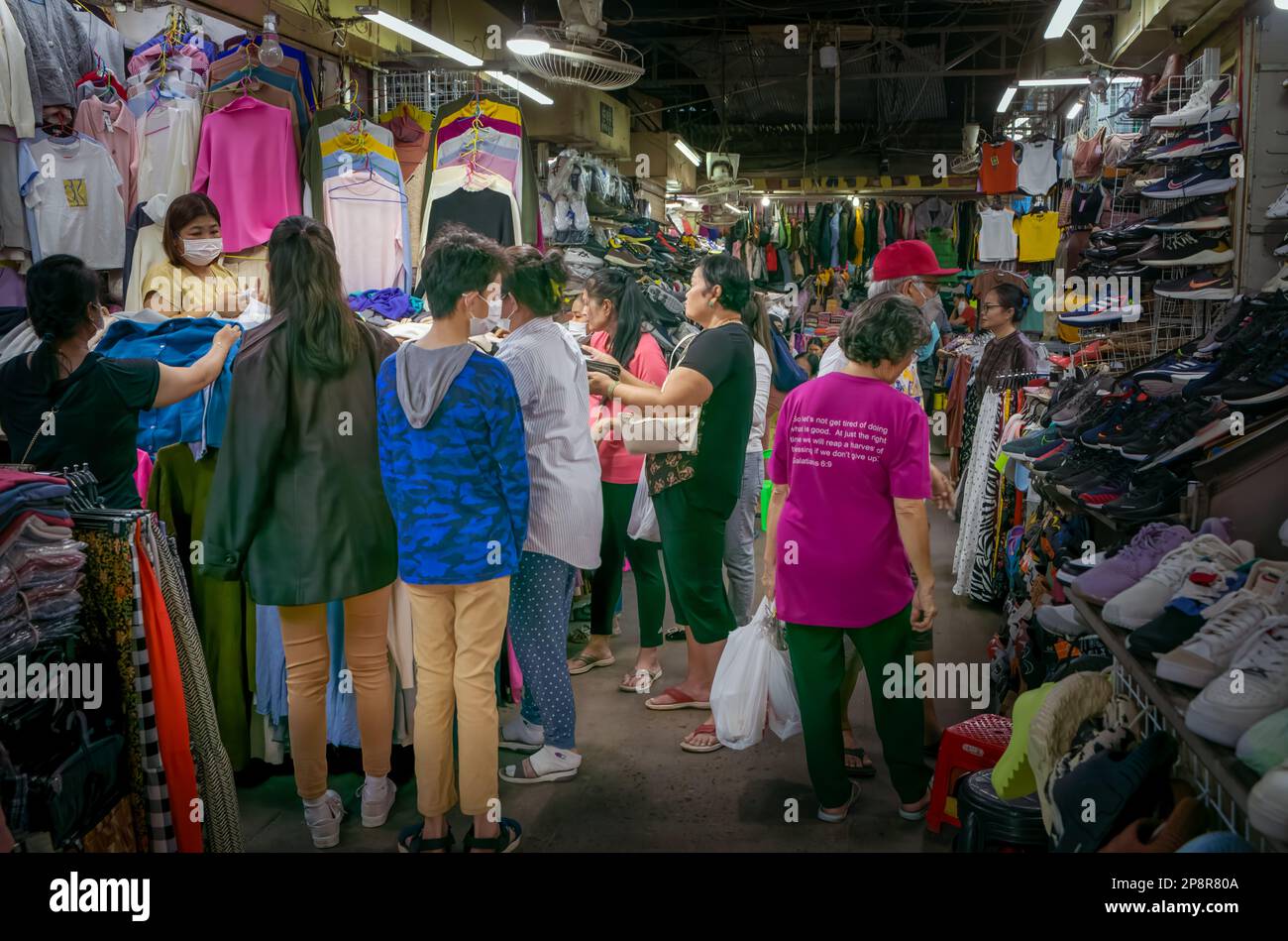 A crowd of shoppers rummage through clothes on a stall within the Russian Market in Phnom Penh, Cambodia. Stock Photo