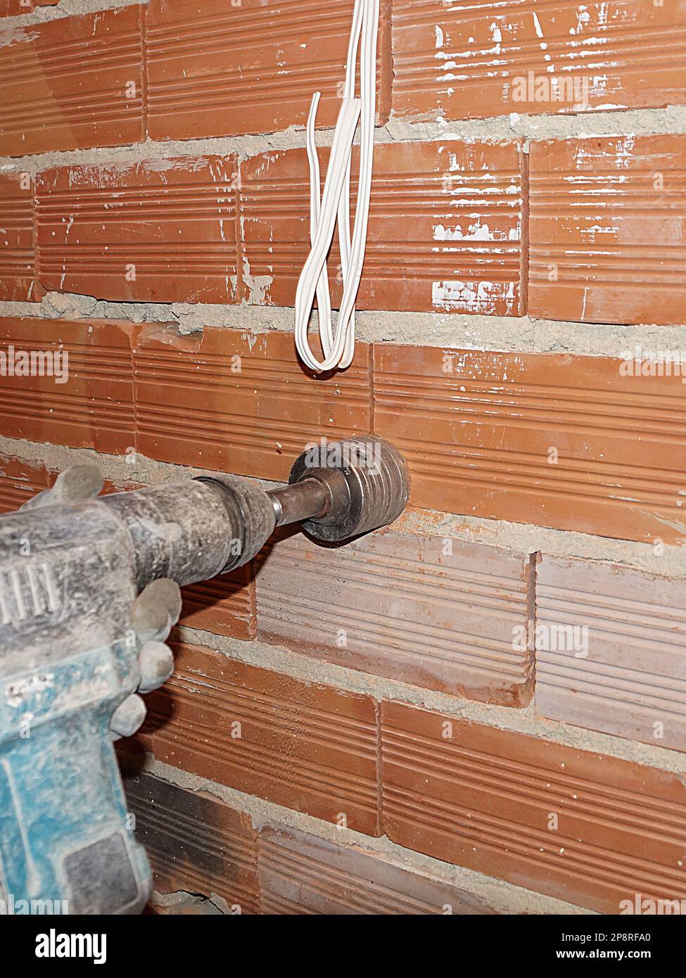 drilling a hole for an outlet in a brick wall with a puncher Stock
