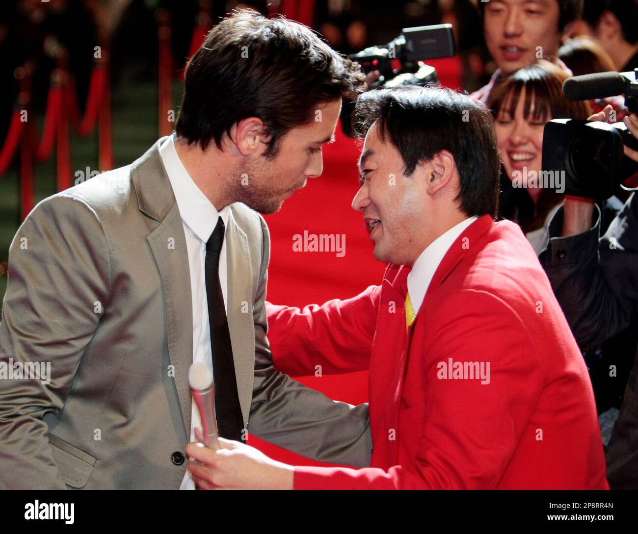 Canadian actor Justin Chatwin, left, reacts as he is hugged by a Japanaese TV interviewer upon arriving at the world premiere of Dragonball Evolution, the Hollywood adaptation of the famed Japanese cartoon series, in Tokyo, Japan, Tuesday, March 10, 2009. (AP Photo/Itsuo Inouye) Stock Photo