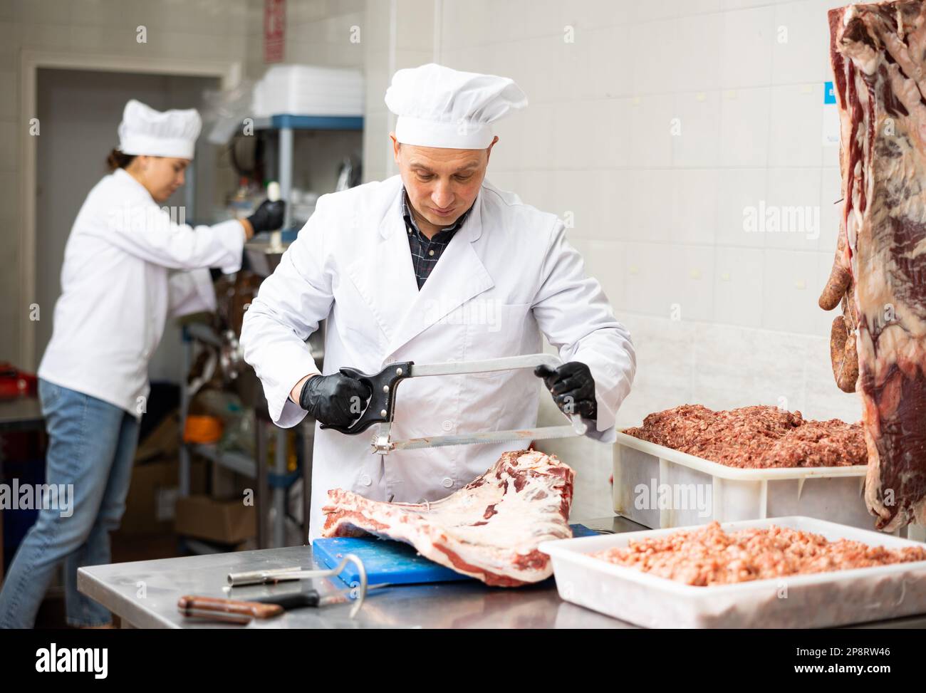 Butchery worker sawing beef ribs at cutting table Stock Photo - Alamy