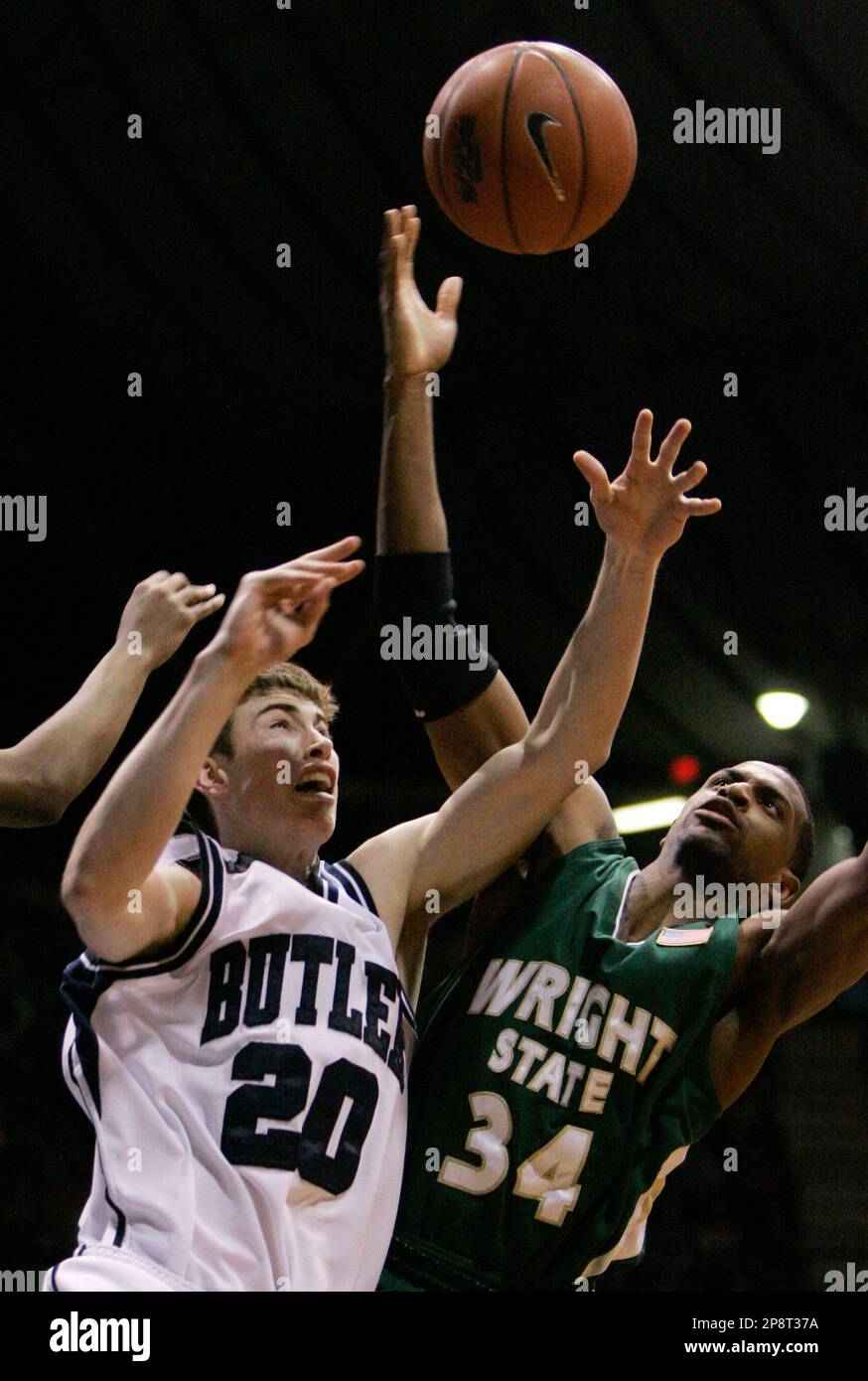 Butler forward Gordon Hayward, left, hangs on the rim after dunking over  the defense of Wisconsin-Milwaukee forward Jason Averkamp in the first half  of an NCAA college basketball game in the semifinals