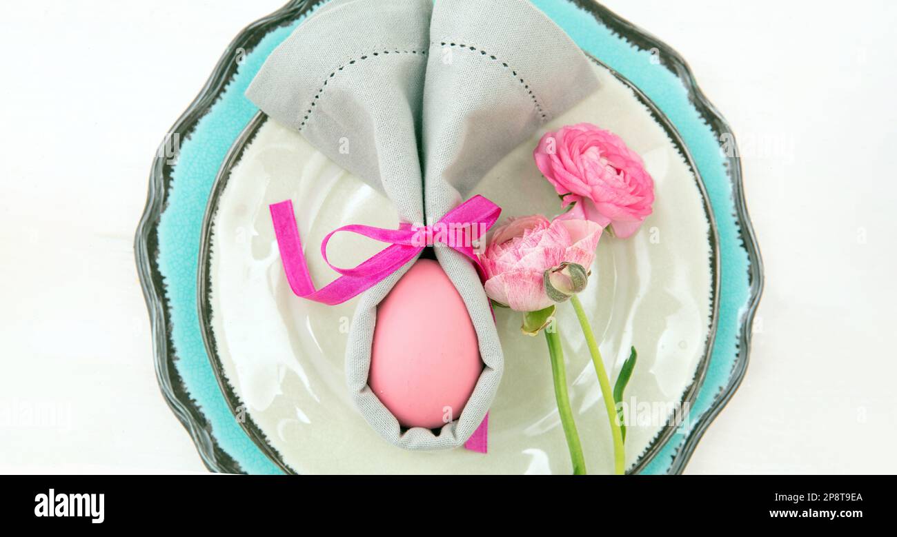 Easter table setting and decoration, Easter egg in a gray napkin on plates set, white background Stock Photo
