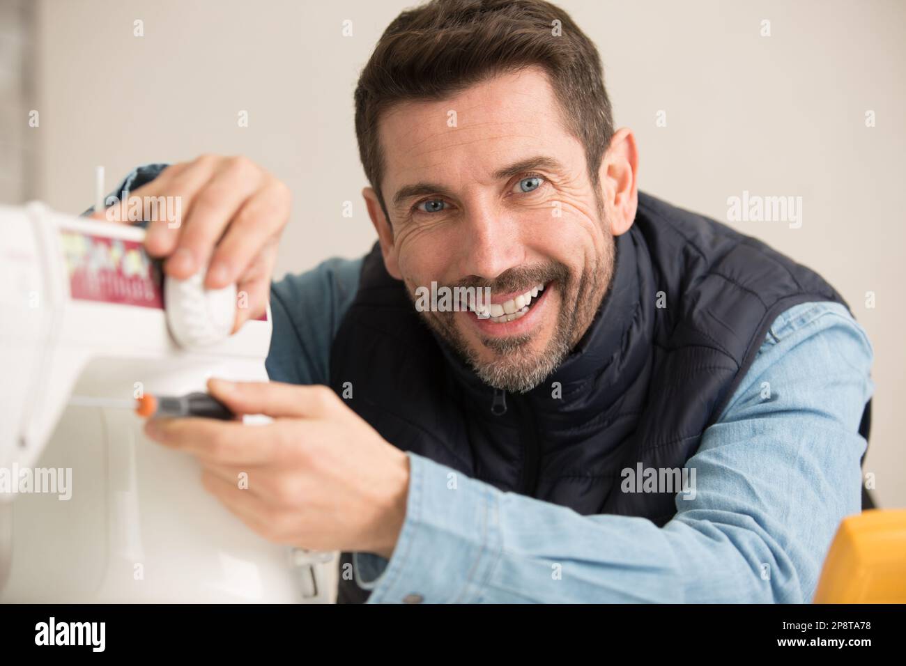 mechanic repairing sewing machine with screwdriver Stock Photo