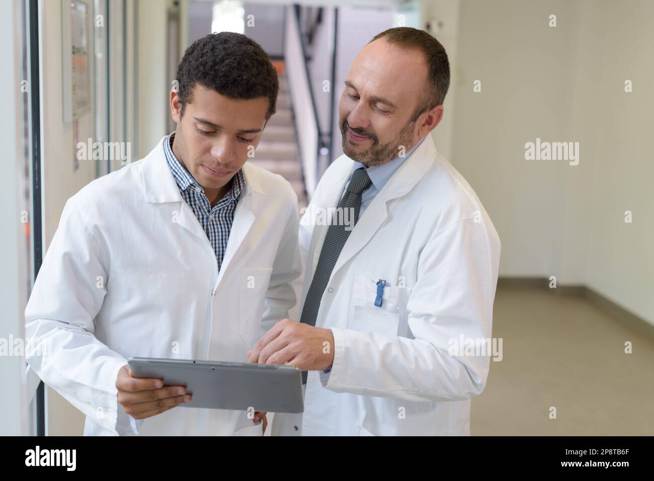 senior and junior doctors looking at tablet pc Stock Photo