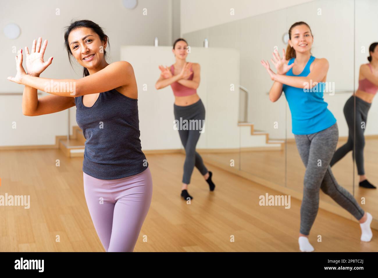 Cheerful hispanic woman practicing vigorous dance in group class Stock Photo