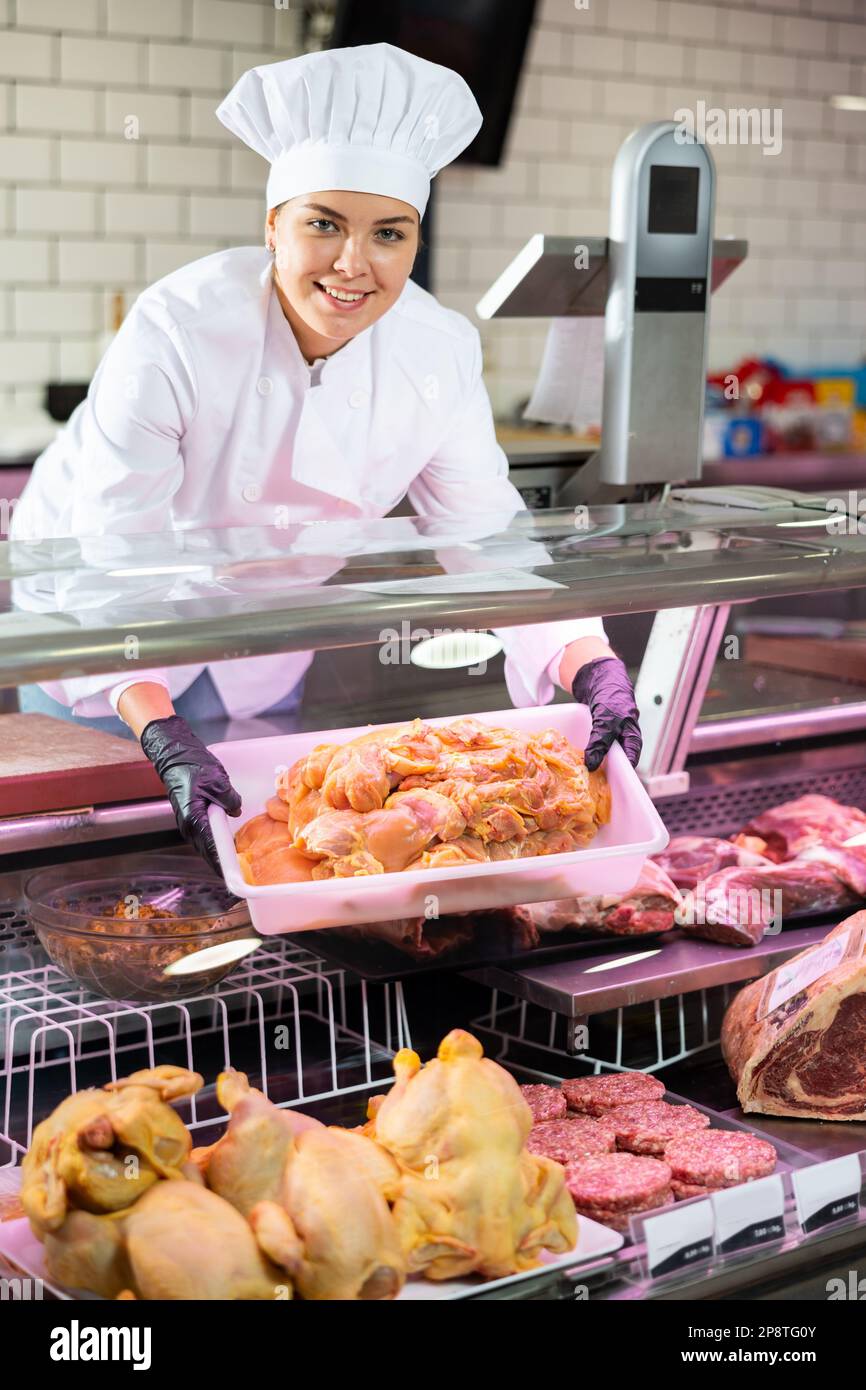 Smiling female butcher holding chicken fillet in butcher shop Stock ...