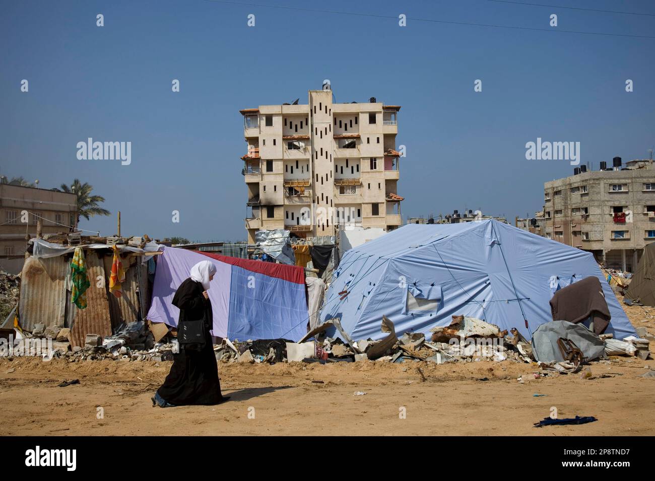 A Palestinian girl walks in front of tents, set up to shelter people ...