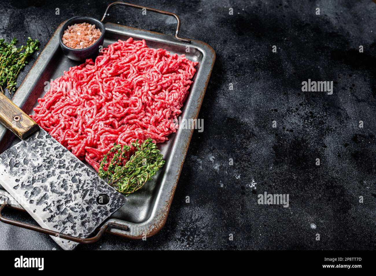 Unccoked Mince Ground meat, raw mincemeat beef and pork in a kitchen tray. Black background. Top view. Copy space. Stock Photo