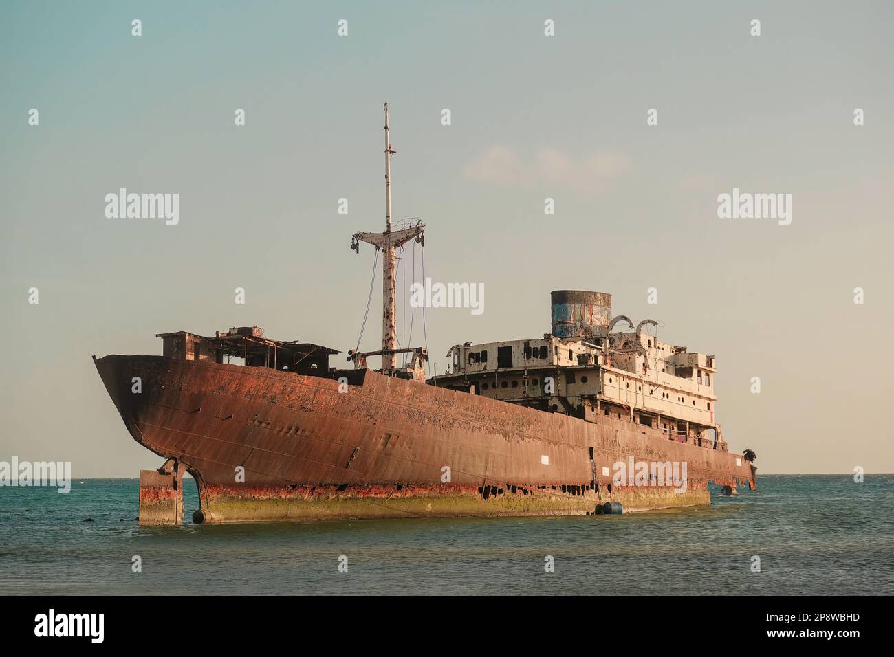 Abandoned old rusty ghost ship (Temple Hall) in 1977 due to a shipwreck near Arrecife, Lanzarote, Spain. Clear sky with sunset Stock Photo