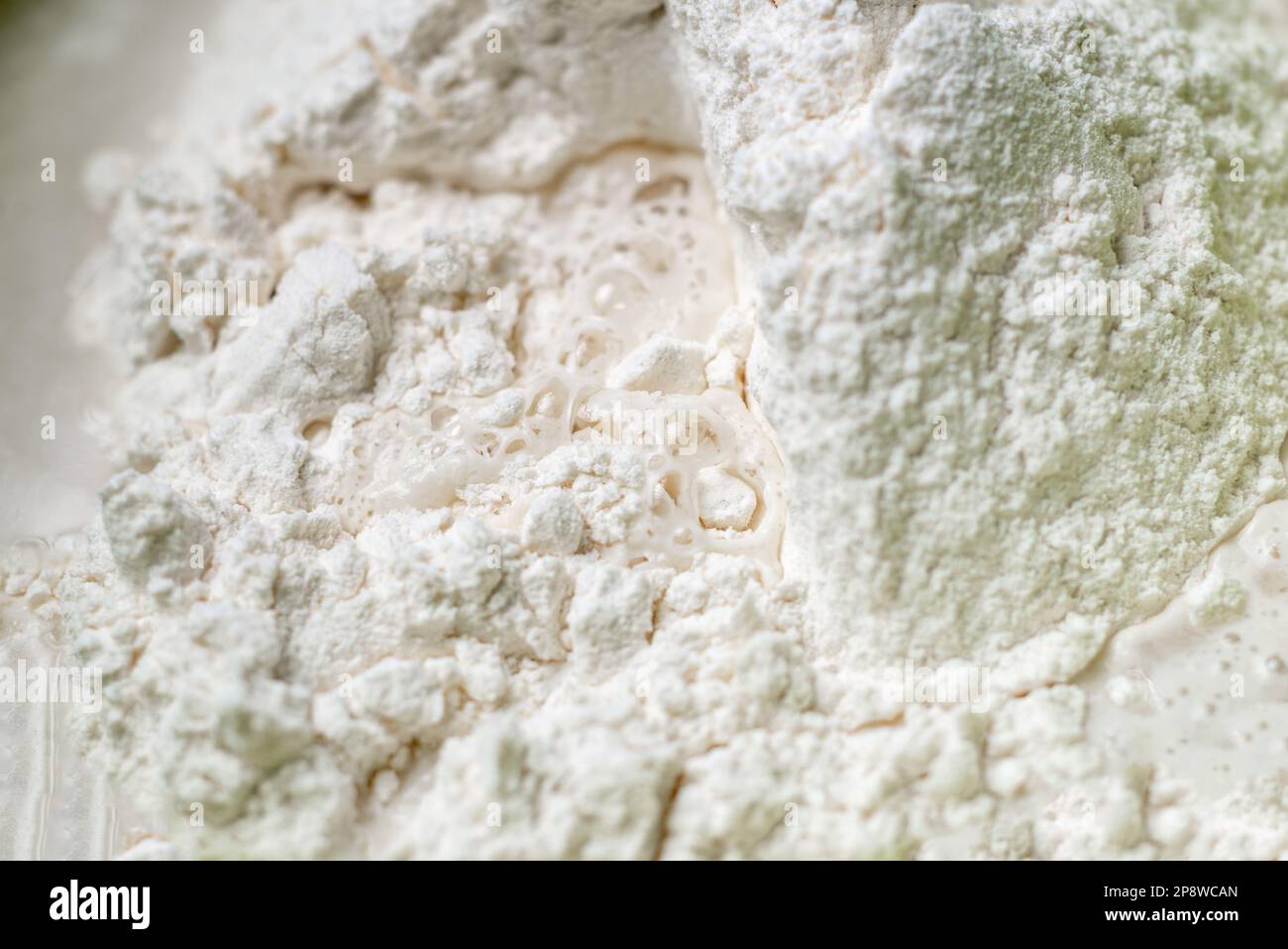 water is added to flour. Kneading dough for cooking. Closeup. Flour