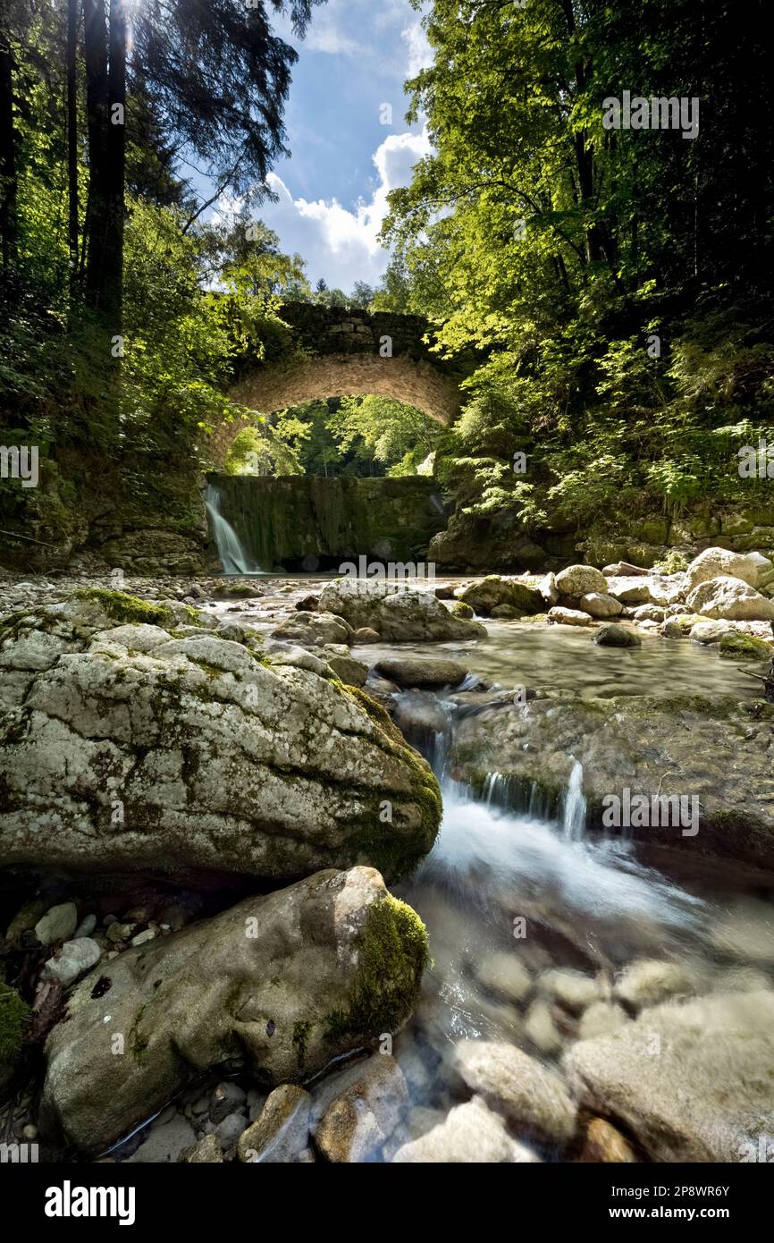 The Astico stream and the ancient stone bridge along the nature trail 'The water path'. Carbonare, Folgaria, Alpe Cimbra, Trentino, Italy. Stock Photo