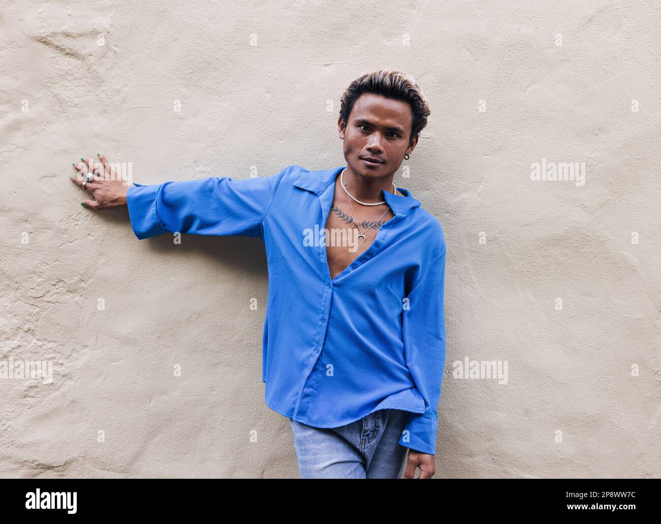 Young handsome guy leaning against a wall and looking at camera Stock Photo