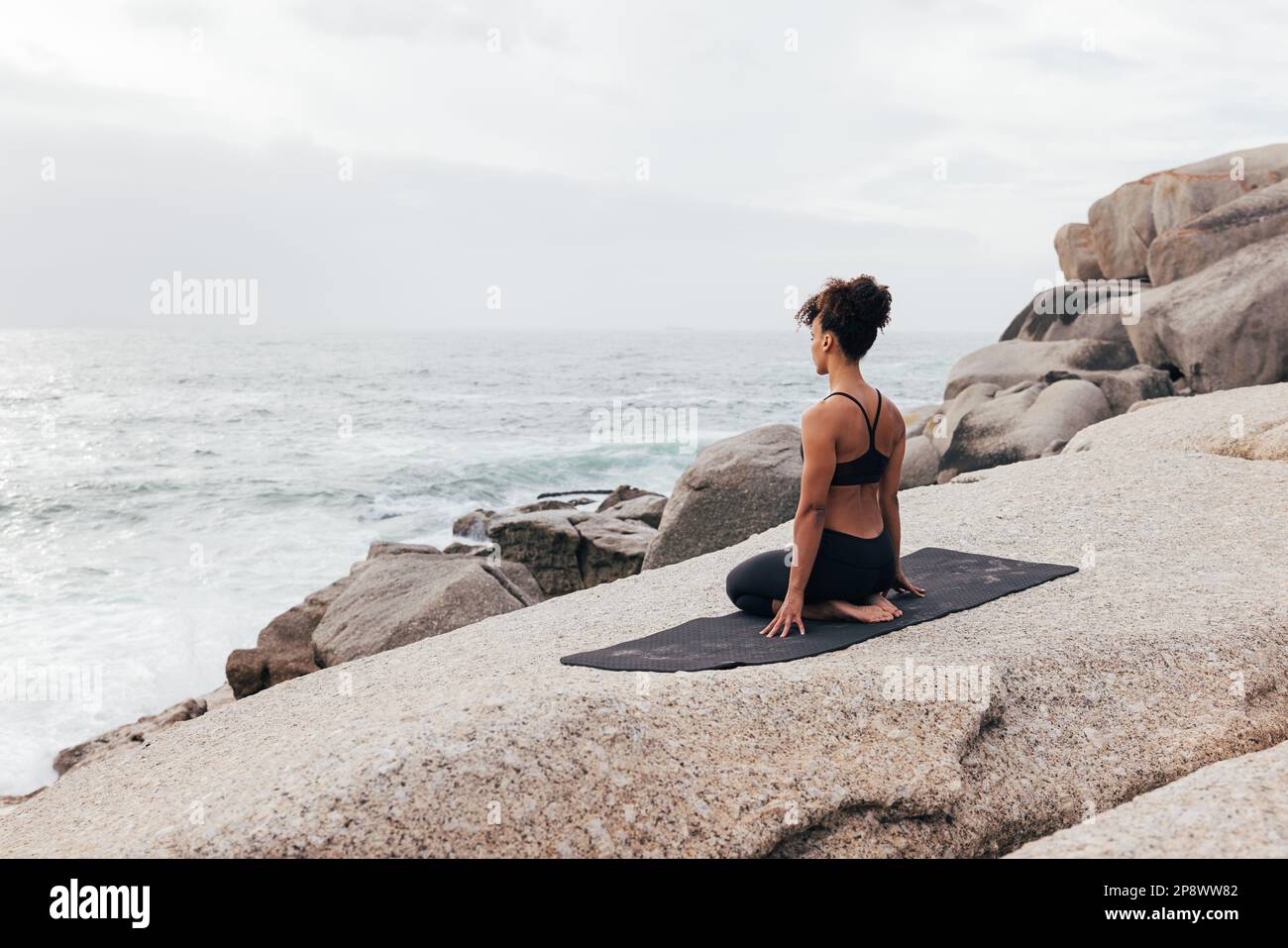 Fit woman on a mat at ocean. Slim female relaxing after yoga exercises  stock photo