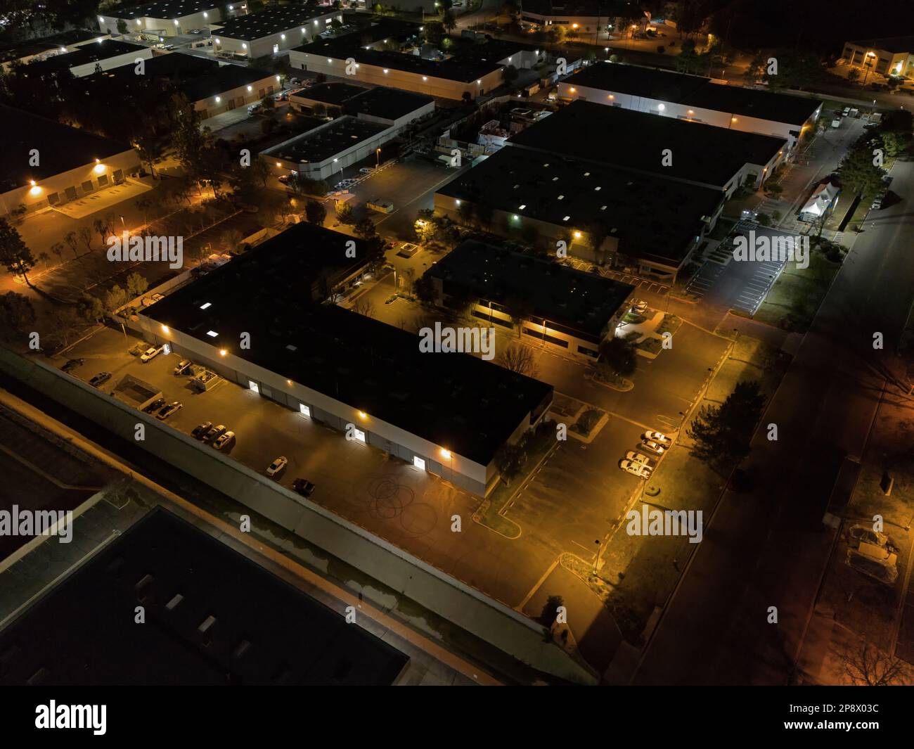 Nondescript warehouses and office buildings are shown in an industrial business park from an overhead view at night. Stock Photo