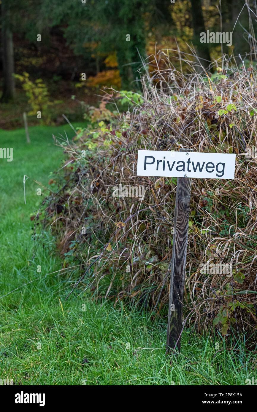 Closed woodland path with a sign on the meadow Stock Photo