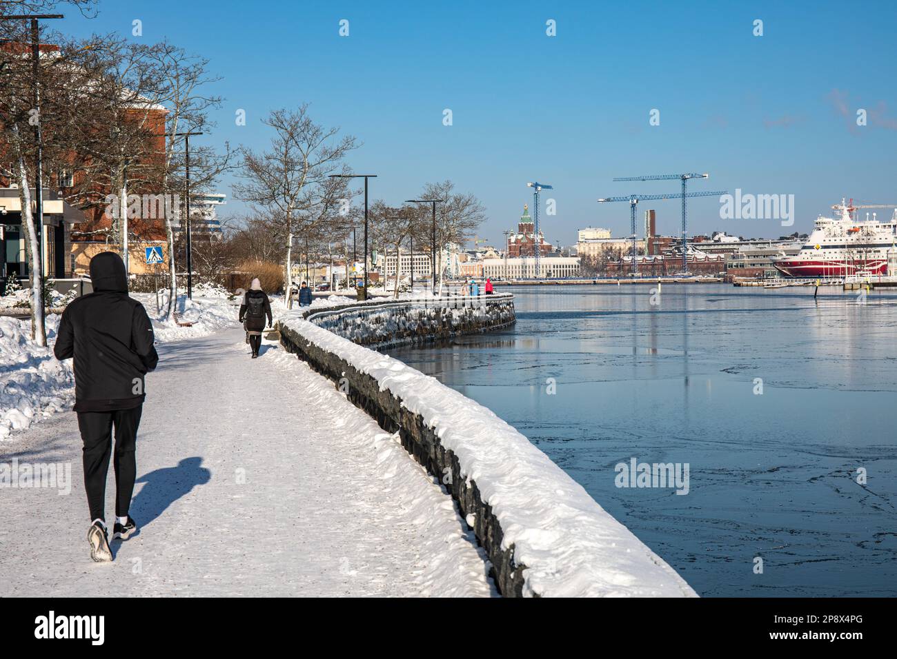 People jogging and walking on Kaivopuisto promenade on a sunny winter day in Helsinki, Finland Stock Photo