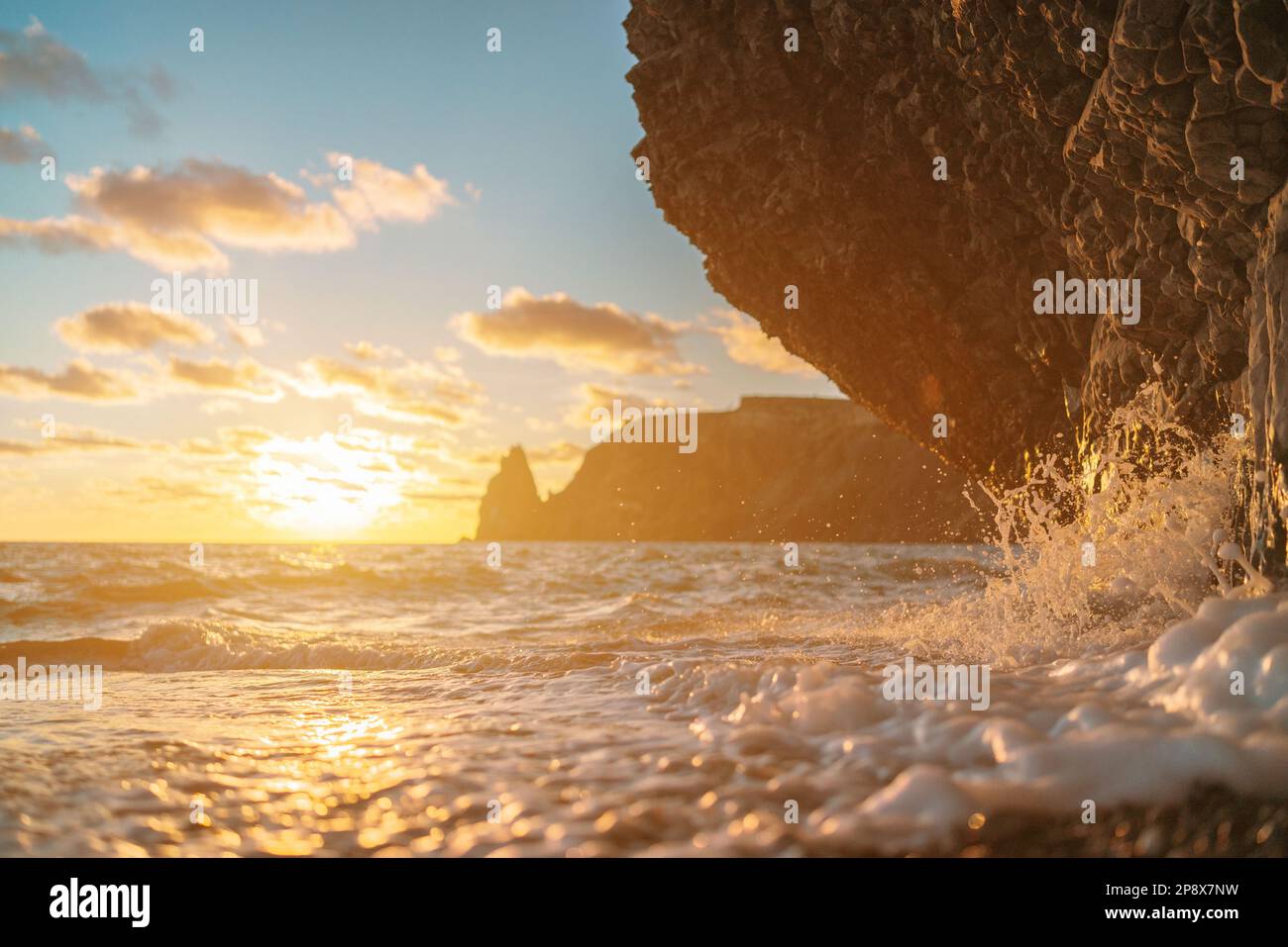 Sea sunset waves with foam. Waves run on pebbles and rock from volcanic ...