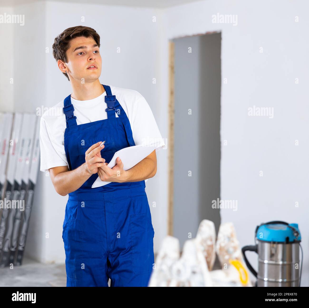 Young foreman making task list during works in building under construction Stock Photo
