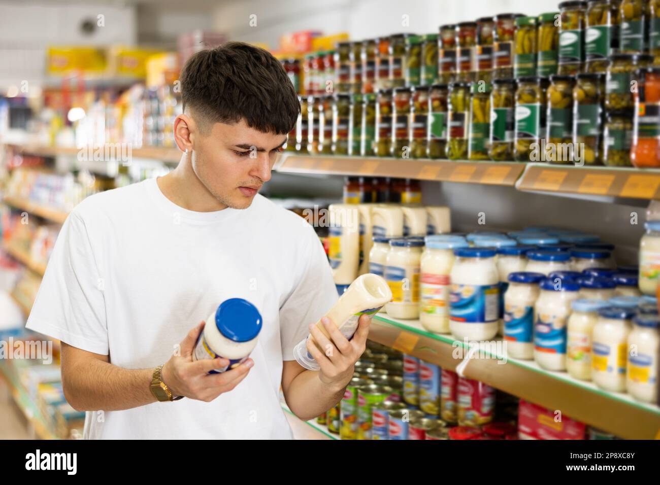 Interested guy reading label of jar of mayonnaise in supermarket Stock ...