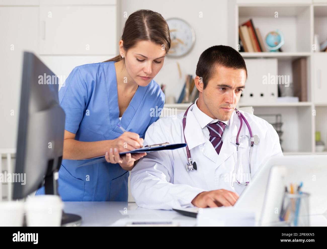 Two physicians working with case histories on laptop Stock Photo
