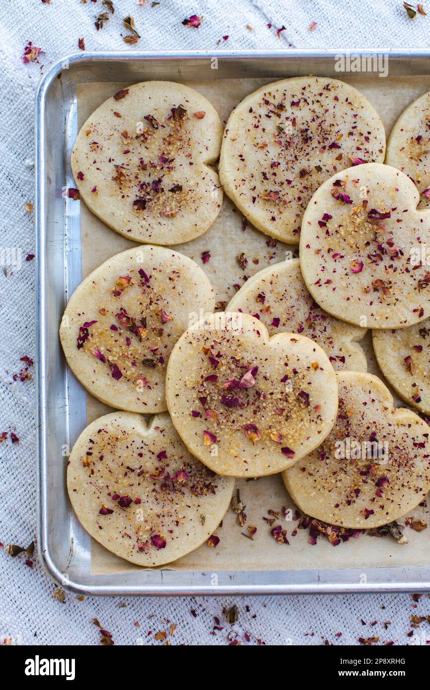 Heart shaped cookies on a tray sprinkled with rose petals. Stock Photo