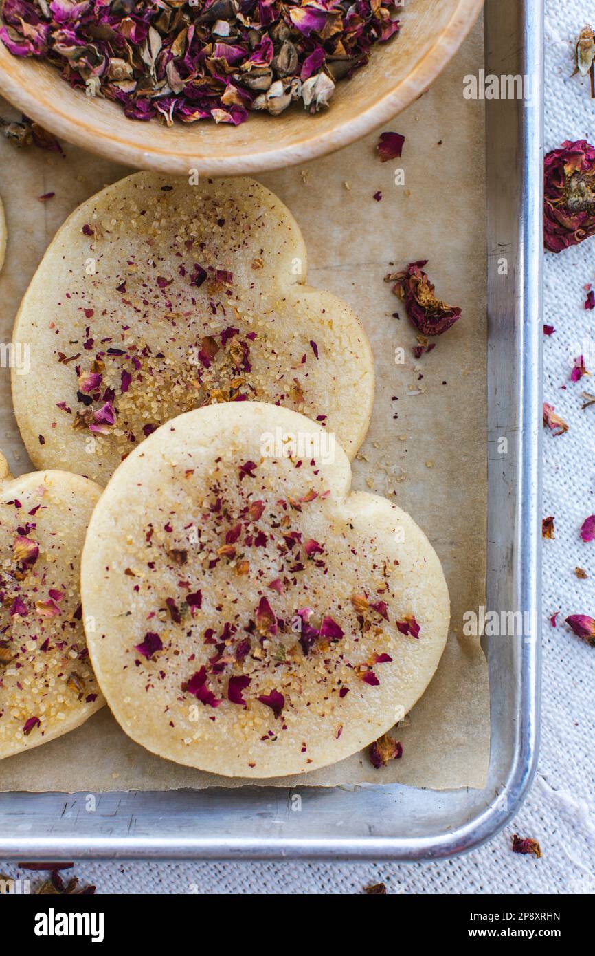 Heart shaped cookies on a tray sprinkled with rose petals. Stock Photo