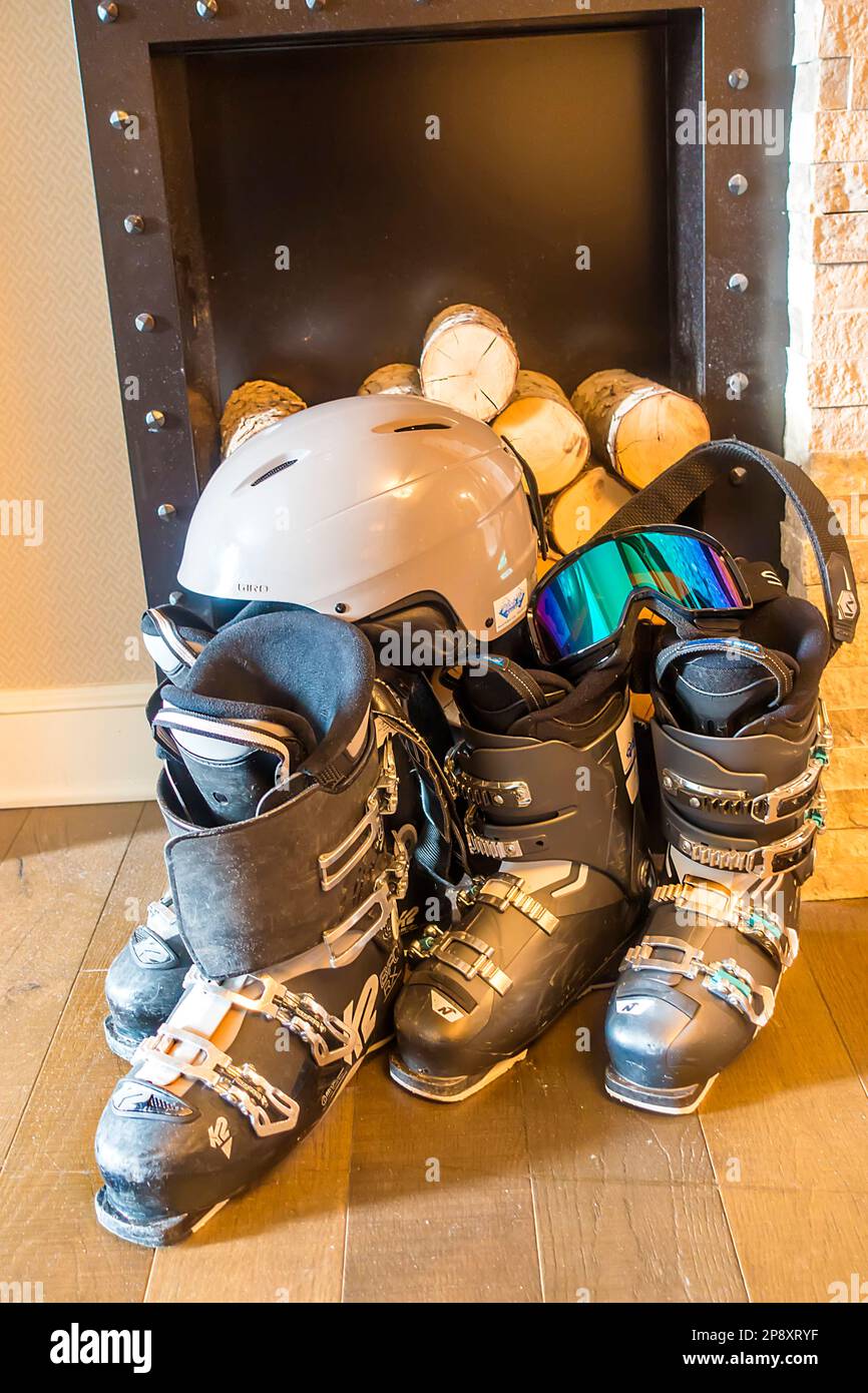 Ski boots, helmet and goggles in front of logs inside home Stock Photo