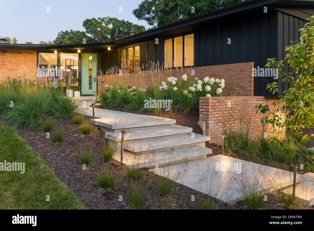 New front steps leading to midcentury modern house lit up at dusk