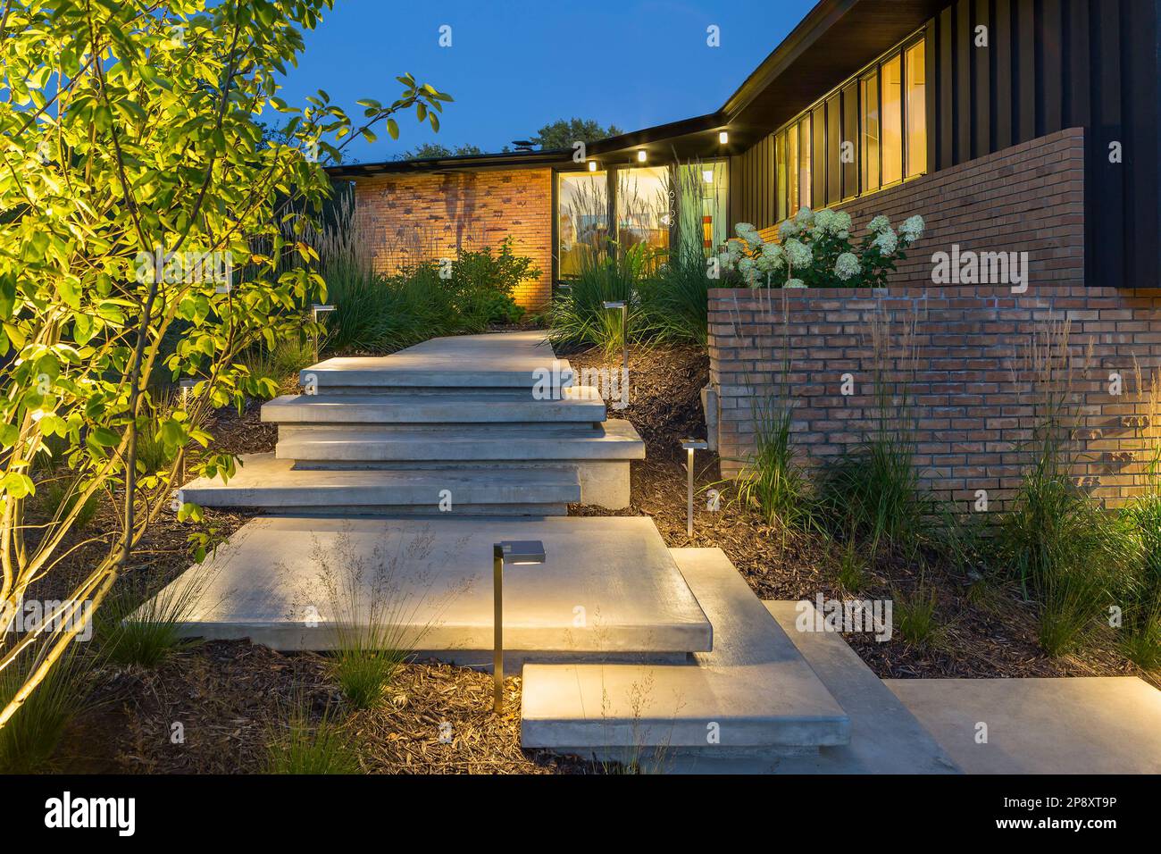 New front steps leading to midcentury modern house lit up at night