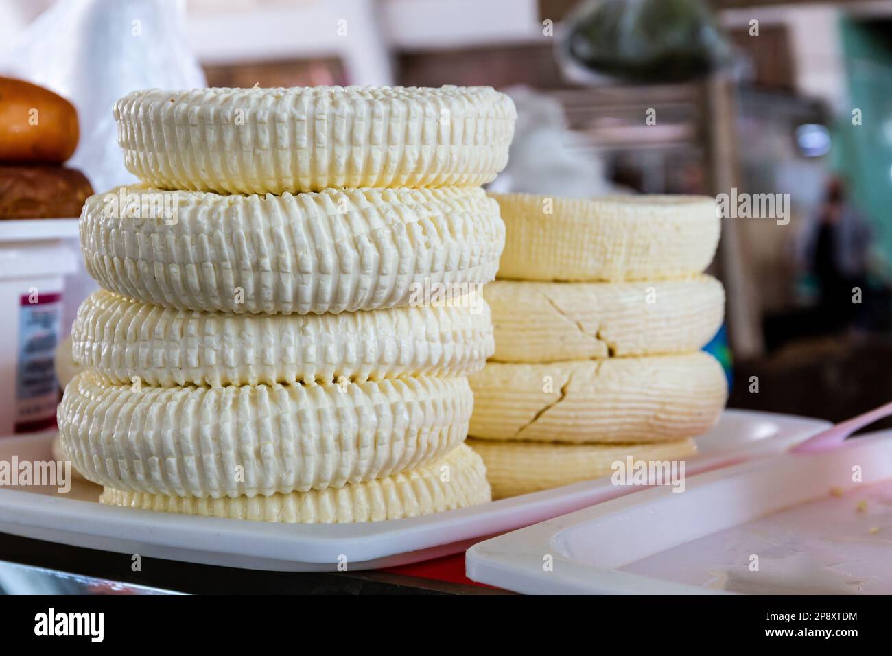 Georgian Sulguni cheese round discs stack on a market stall in Kutaisi Central Market (Green Bazaar,  Mtsvane Bazari). Stock Photo