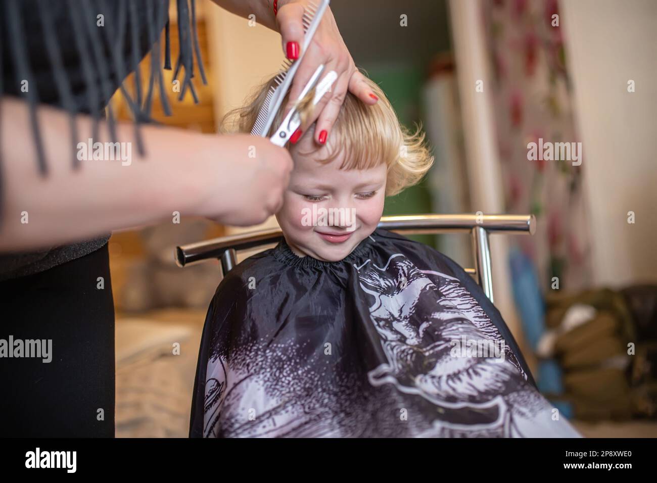 The hands of a hairdresser holding the child's bangs before cutting. hair stylist. Stock Photo