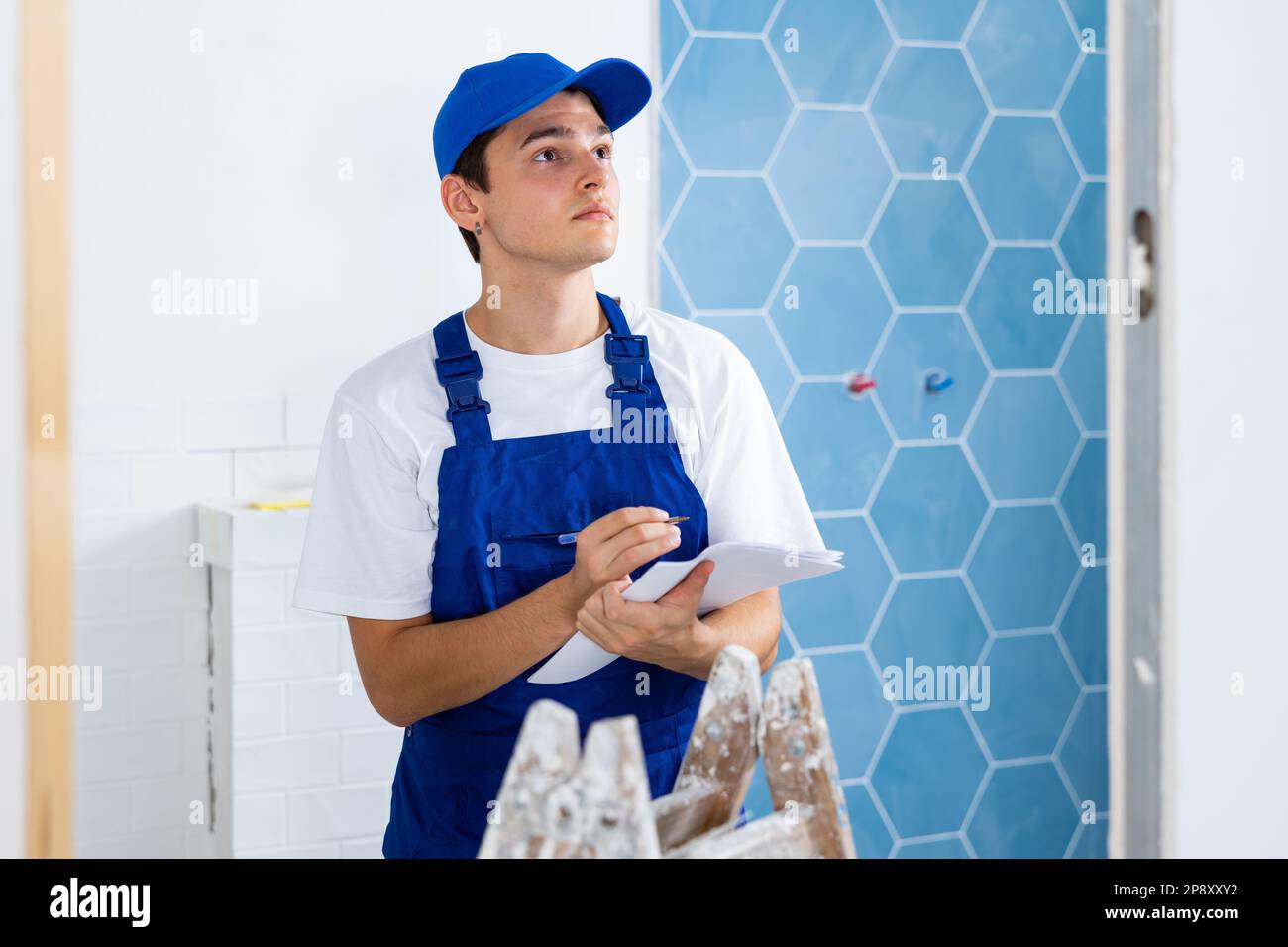 Young builder making checklist while planning indoor building overhaul Stock Photo