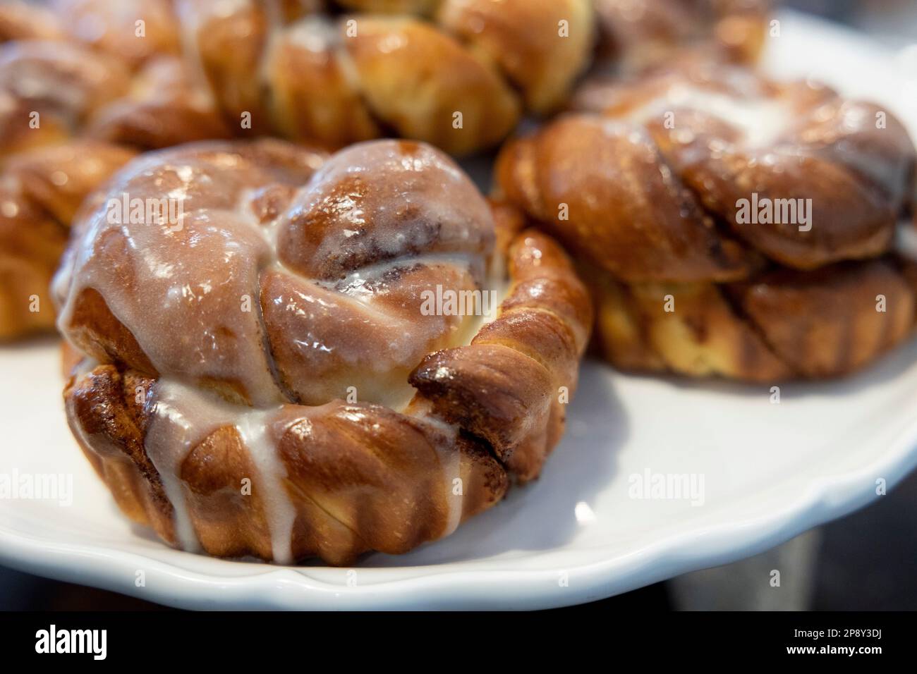 Cinnamon buns with white icing on a white plate Stock Photo
