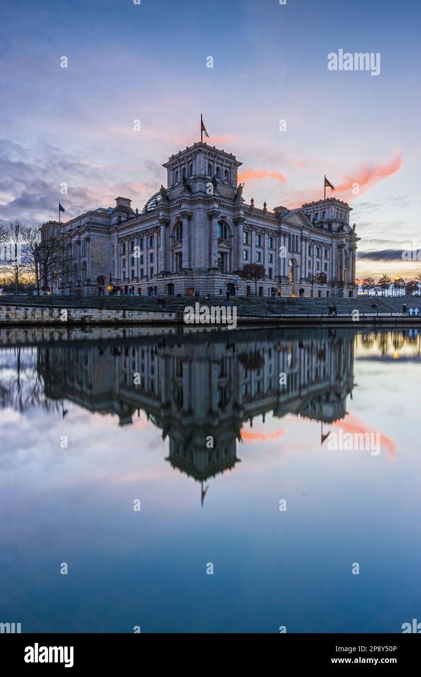 Government district in the capital of Germany. River Spree with reflection on water surface from Reichstag in Berlin at sunset. reddish orange clouds Stock Photo