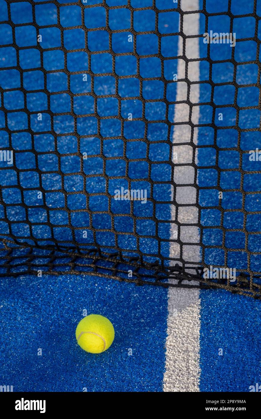 Ball next to the net of a blue paddle tennis court. Stock Photo