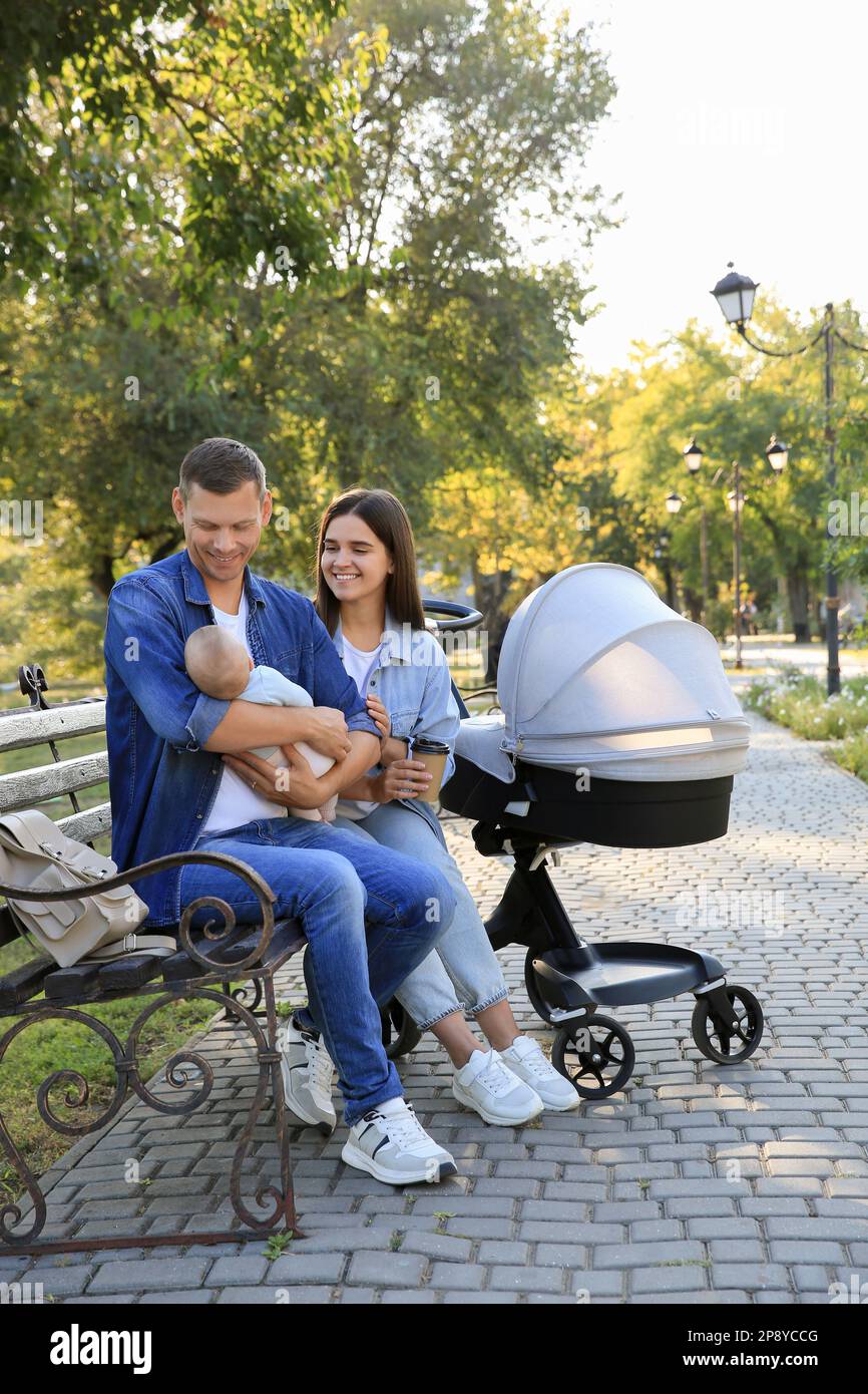 Happy parents with their baby on bench in park Stock Photo - Alamy