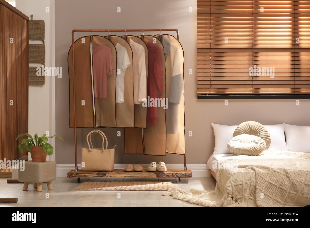 Garment bags with clothes hanging on rack in bedroom Stock Photo Alamy