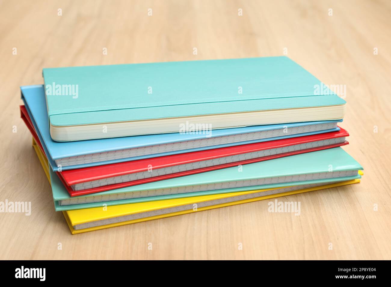 Stack of colorful planners on wooden table Stock Photo
