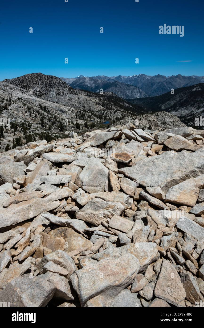 Pile of Boulders on Top of Kennedy Pass with Lake and Mountains in the Distance in Summer Stock Photo