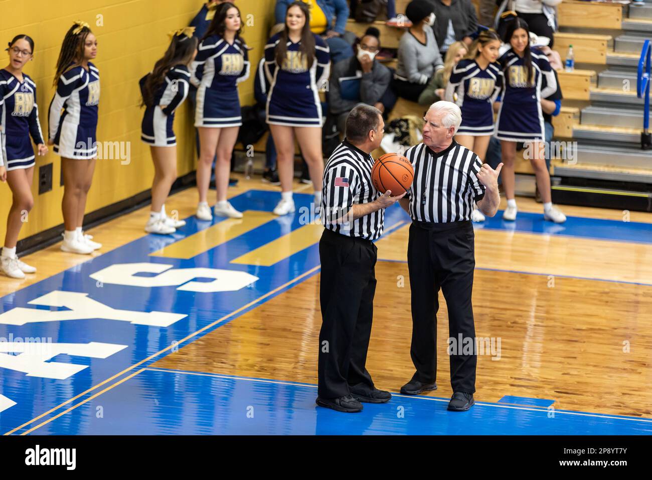 Two IHSAA officials confer on the court in front of the Hammond Noll cheerleaders during a game in the North Judson - San Pierre High School gymnasium. Stock Photo
