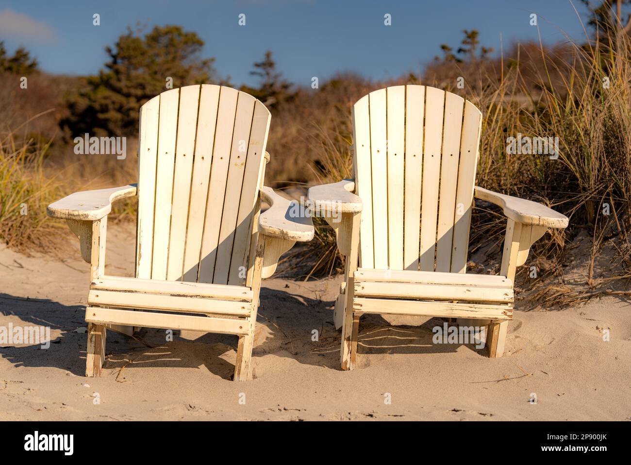 Two white Adirondack chairs on a sandy New England, Cape Code, beach