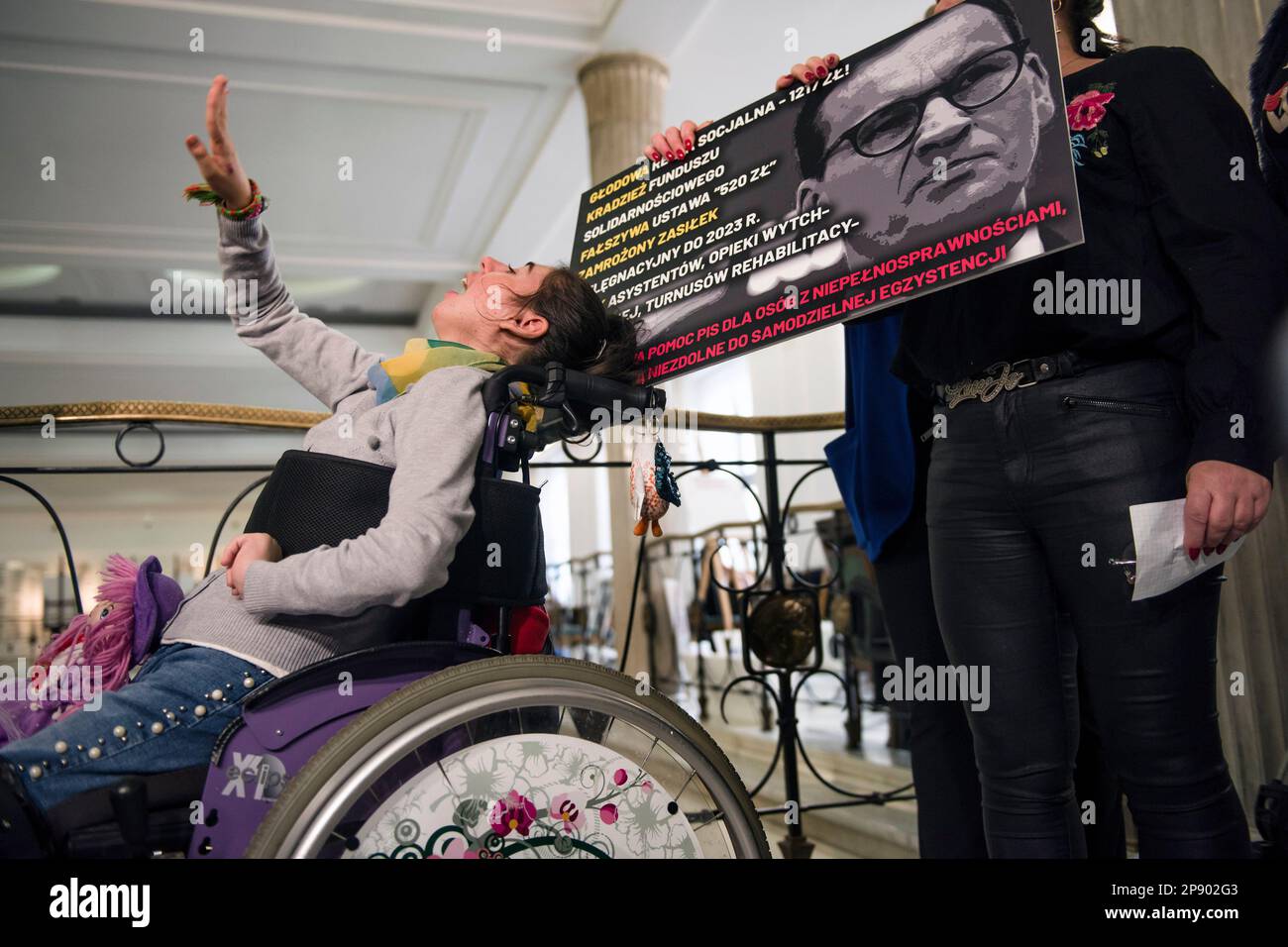 A protesting girl with disability is seen gesturing during a press conference in the Parliament. It is the 4th day since a group of Persons with disabilities along with their parents and care takers gathered in the Sejm (lower house of Parliament) on Monday 6th of March, demanding that the social pension be equalized with the national minimum. Among the protesters in the Sejm is also MP - Iwona Hartwich with her disabled son, Jakub. The PO's (Civic Platform) MP informed during a press conference that people with disabilities are submitting a draft act on social pension, after which almost 200, Stock Photo