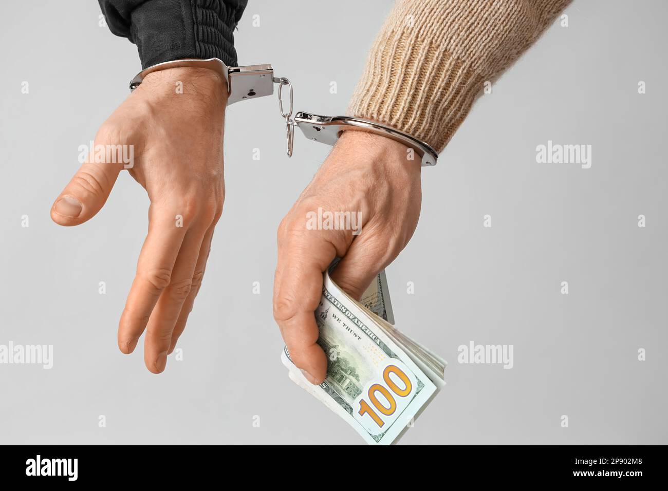 Handcuffed police officer and man with bribe on grey background, closeup Stock Photo