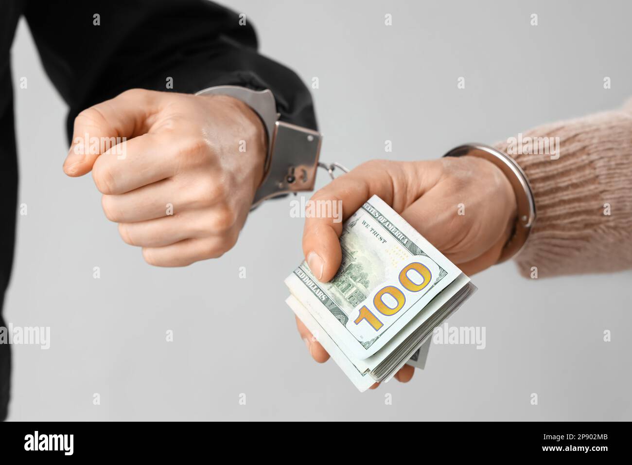 Handcuffed police officer and man with bribe on grey background, closeup Stock Photo