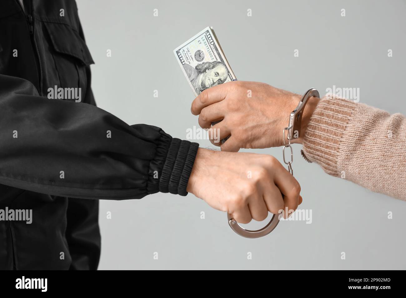 Police officer and man in handcuffs with bribe on grey background, closeup Stock Photo