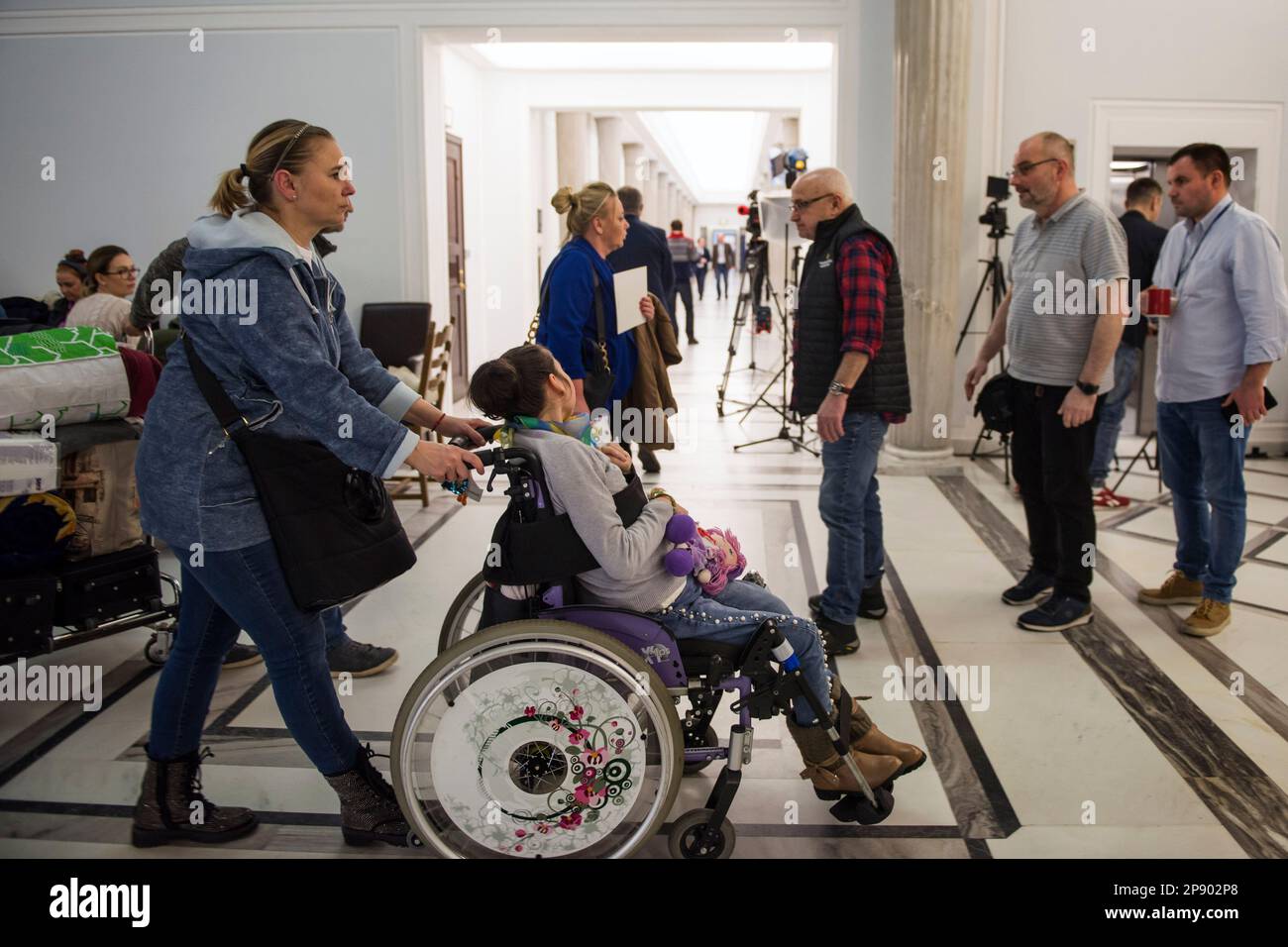 A mother and her daughter with disability leave the protest after 4 days due to deteriorating health. It is the 4th day since a group of Persons with disabilities along with their parents and care takers gathered in the Sejm (lower house of Parliament) on Monday 6th of March, demanding that the social pension be equalized with the national minimum. Among the protesters in the Sejm is also MP - Iwona Hartwich with her disabled son, Jakub. The PO's (Civic Platform) MP informed during a press conference that people with disabilities are submitting a draft act on social pension, after which almost Stock Photo