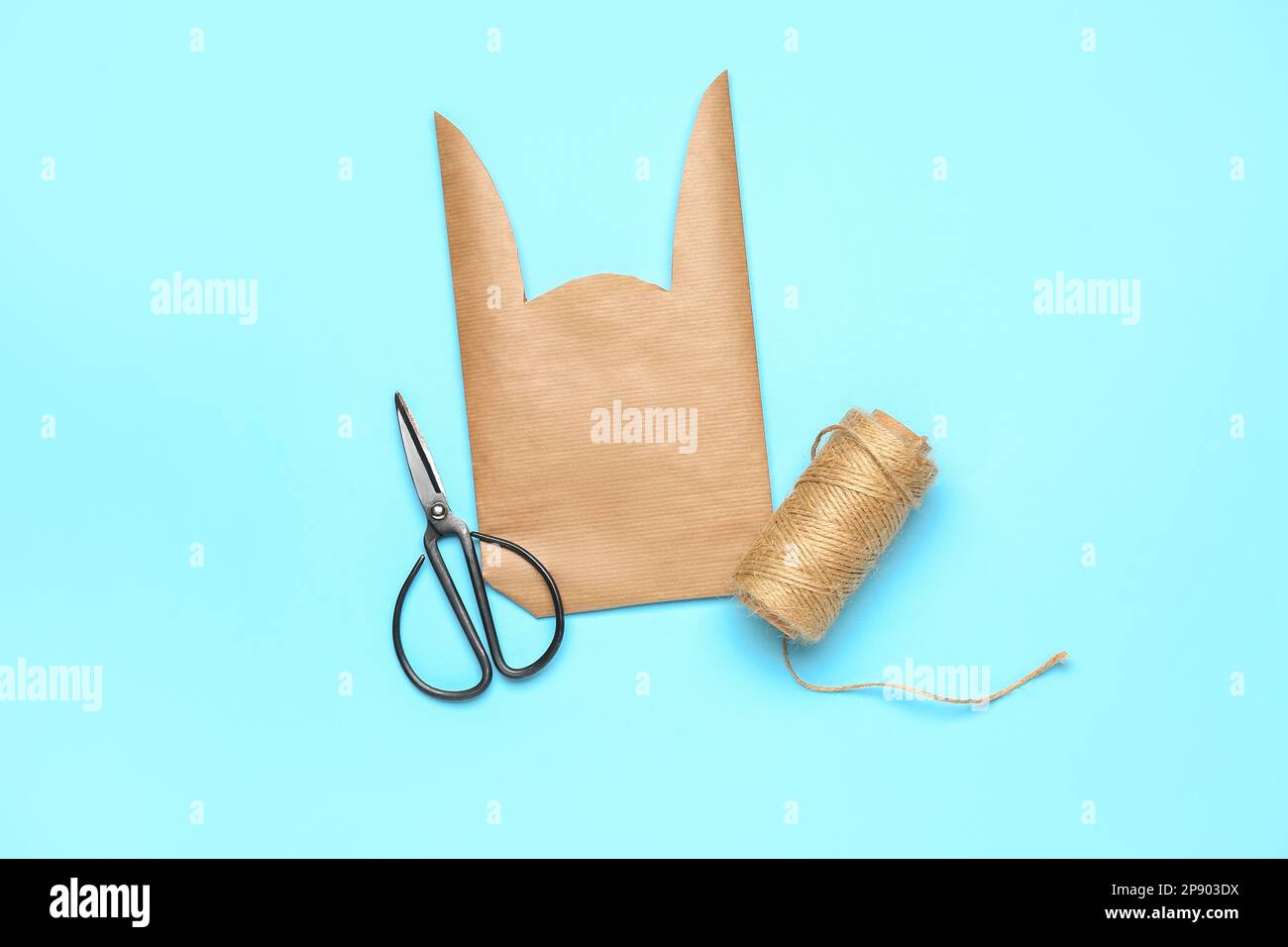 Easter bunny gift bag, scissors and thread on blue background Stock Photo