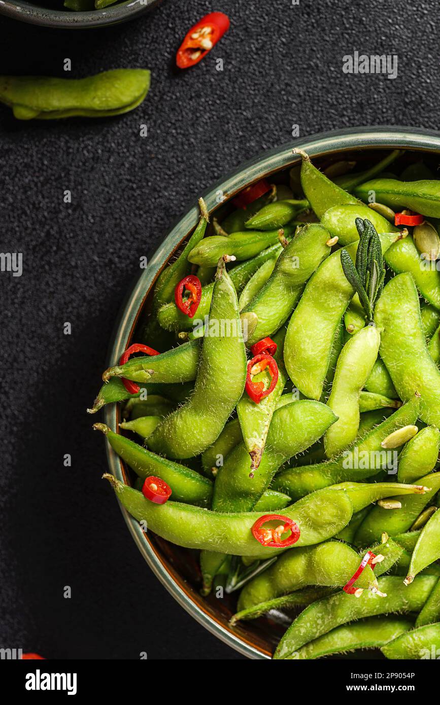 edamame bean salad in pods with chili pepper on a black background