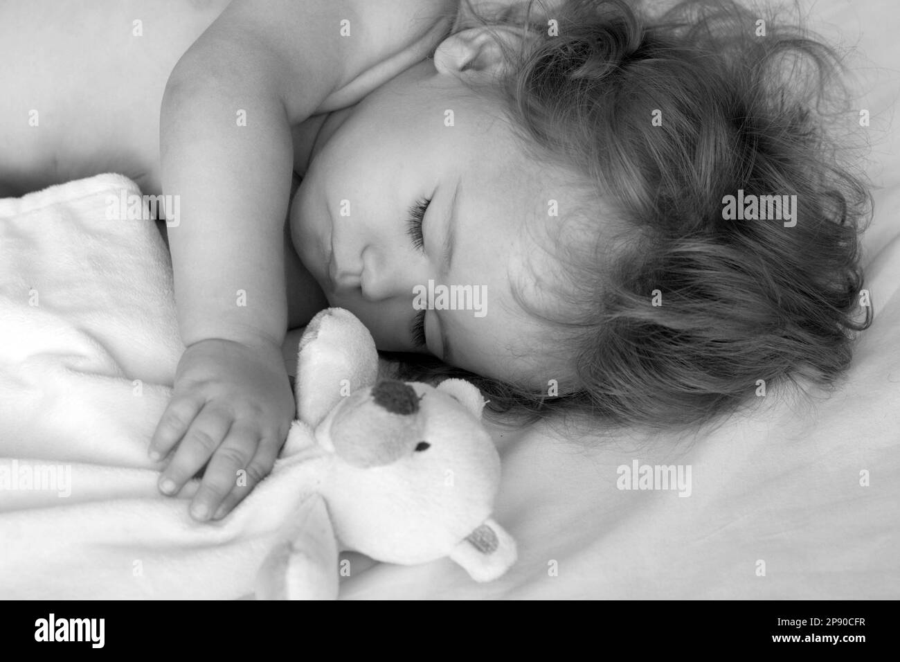 Beautiful baby sleeping in bed at home with toy, child sleeping in the