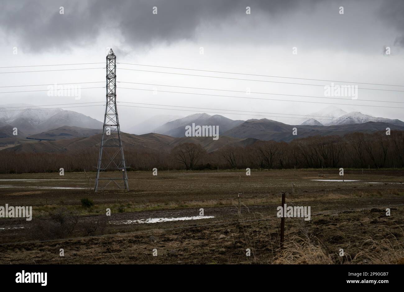 High voltage power pylon and powerlines. Snow-capped mountains in the ...